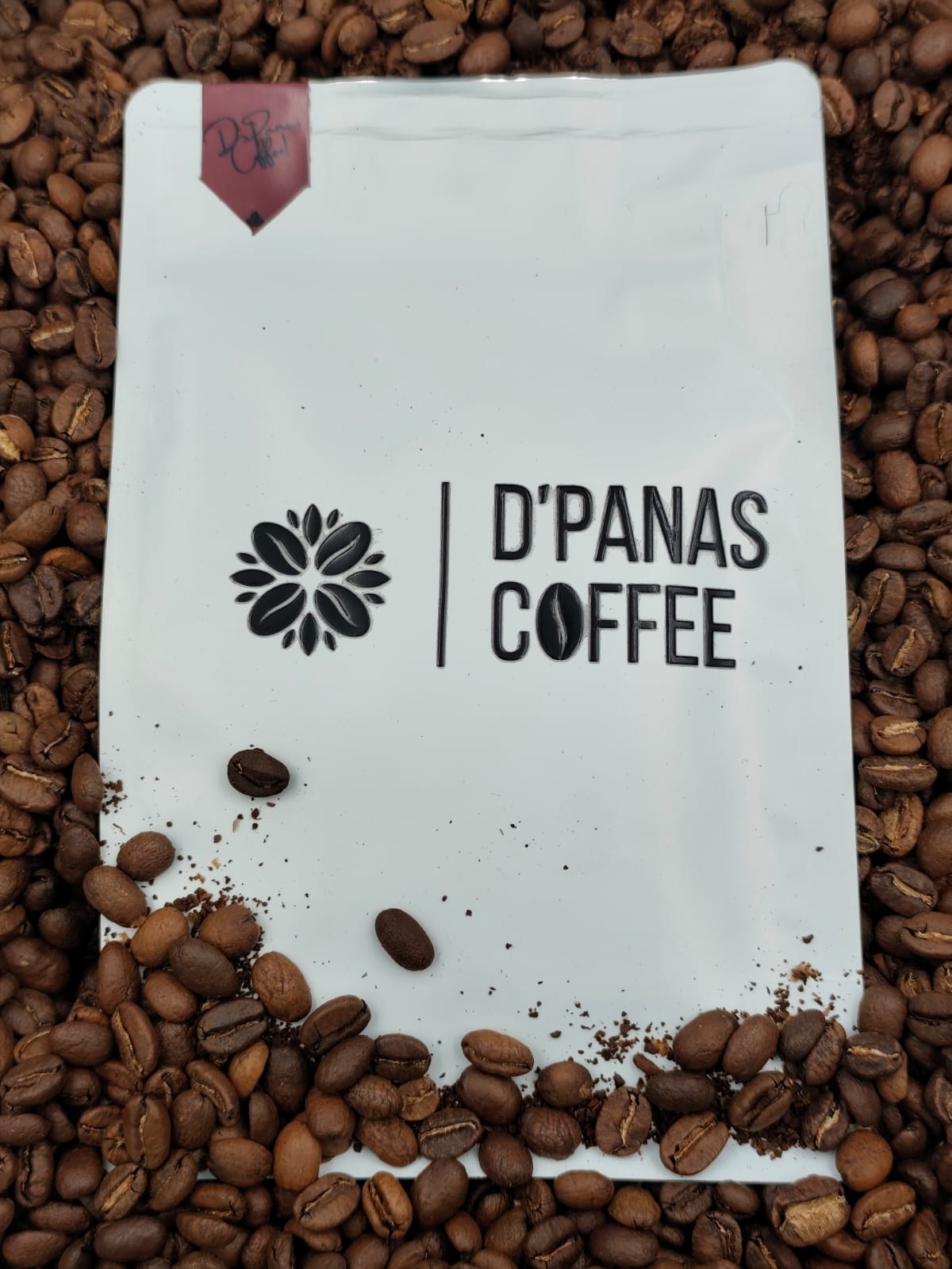 Bolsa de café D'Panas Coffee sobre granos recién tostados